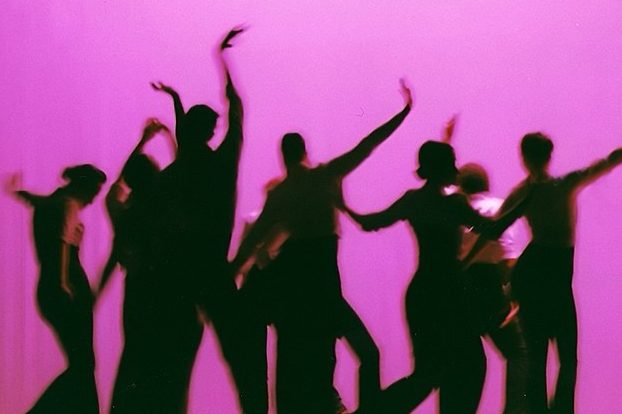 Male and female dancers, dancing in shadow against a purple background