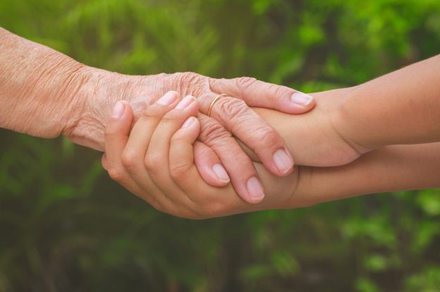 Old and young hands being held in a caring supportive way