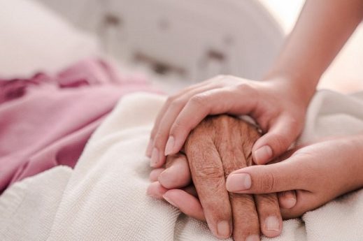 Care worker gently holding an elderly persons hand
