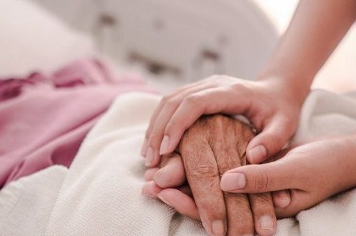 Care worker gently holding an elderly persons hand