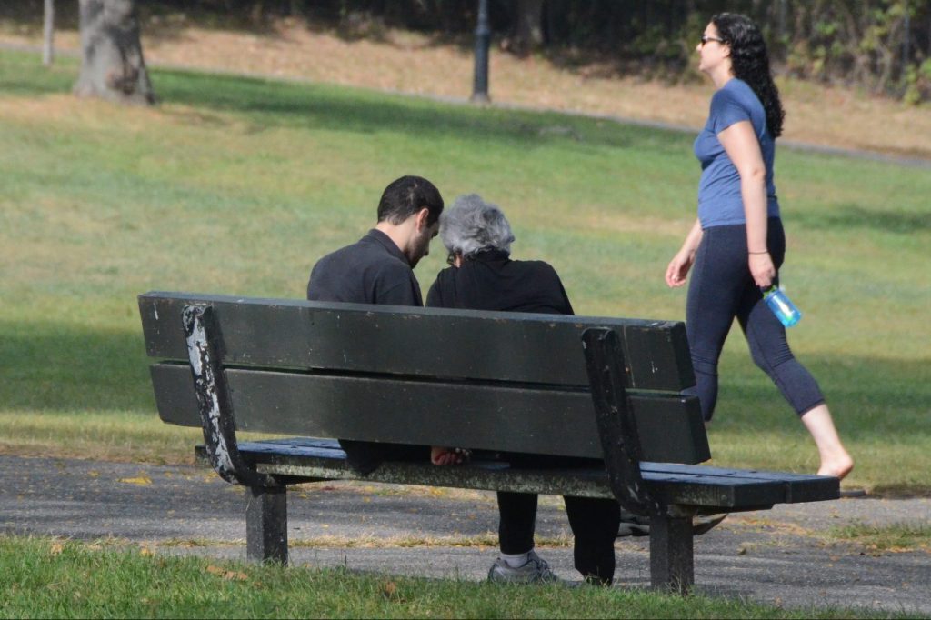 A man and his mother sitting on a park bench