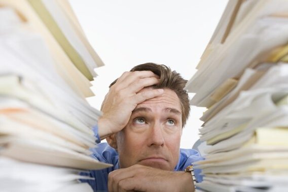 Man staring at mountains of paperwork