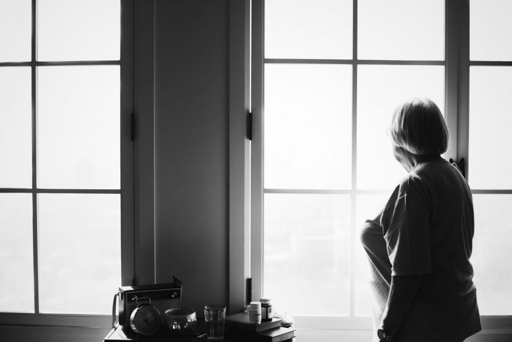 Lonely older woman looking out of the windiw