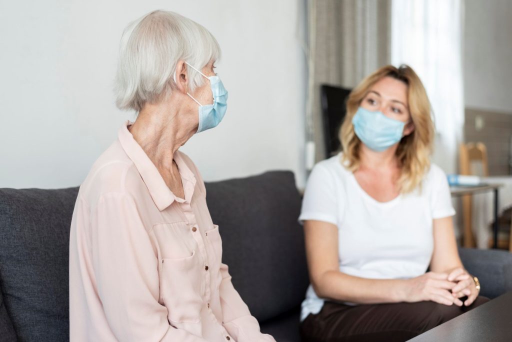 Woman visiting relative in care home, both wearing masks