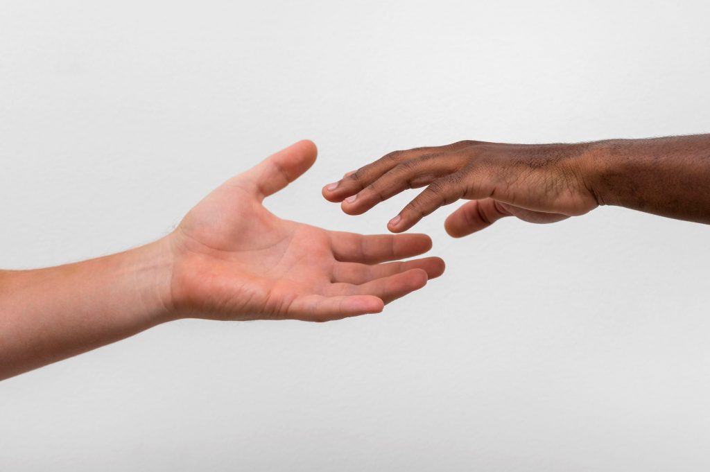 White and black hands raeching towards each other