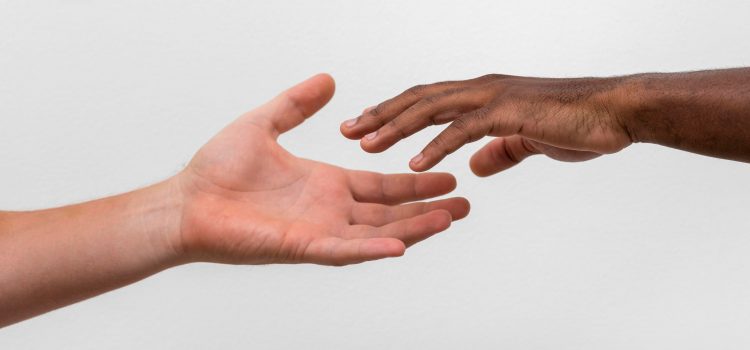 White and black hands raeching towards each other