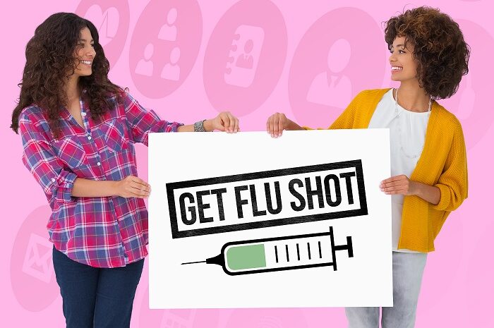 Two women holding a sign saying 'get your flu jab'