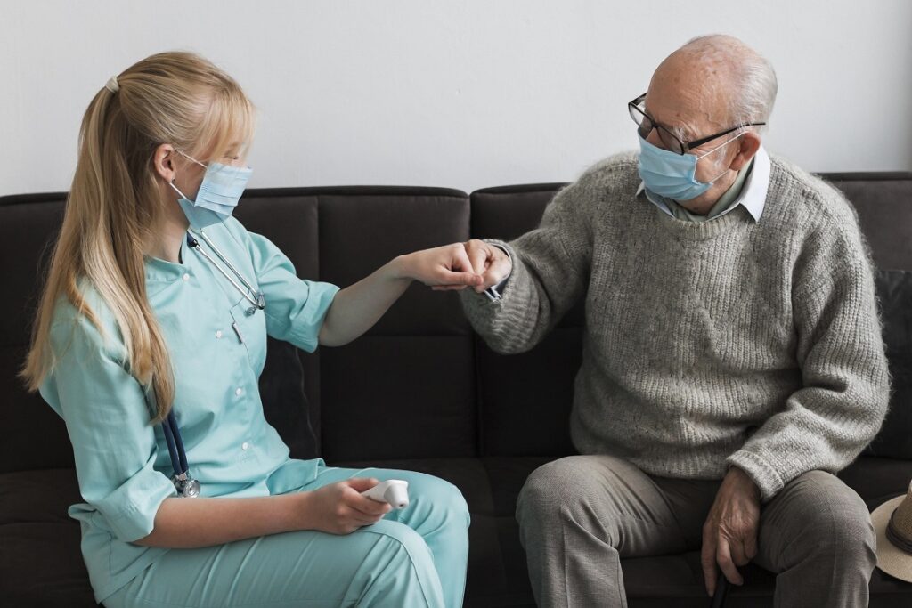 Care home worker and resident fist bump wearing masks