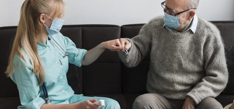 Care home worker and resident fist bump wearing masks