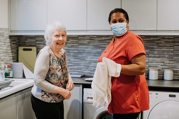 Care walker and resident chatting in kitchen