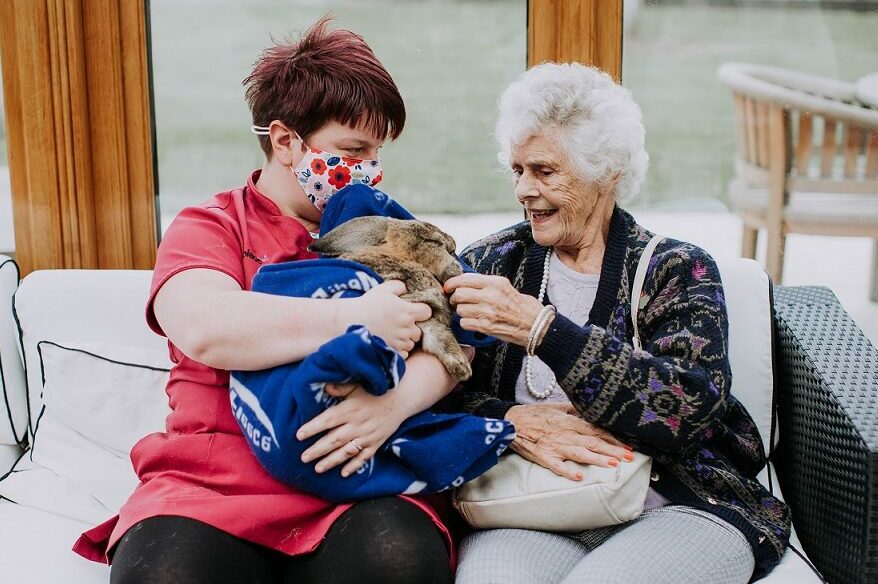 Care staff member and resident enjoying a rabbit