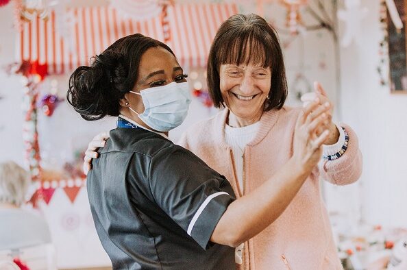 Resident and care worker dancing in PPE