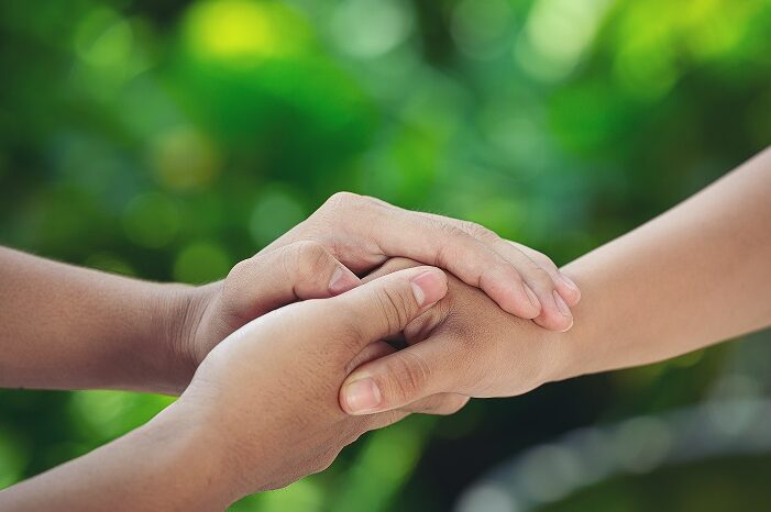 Couple holding hands in green meadow.