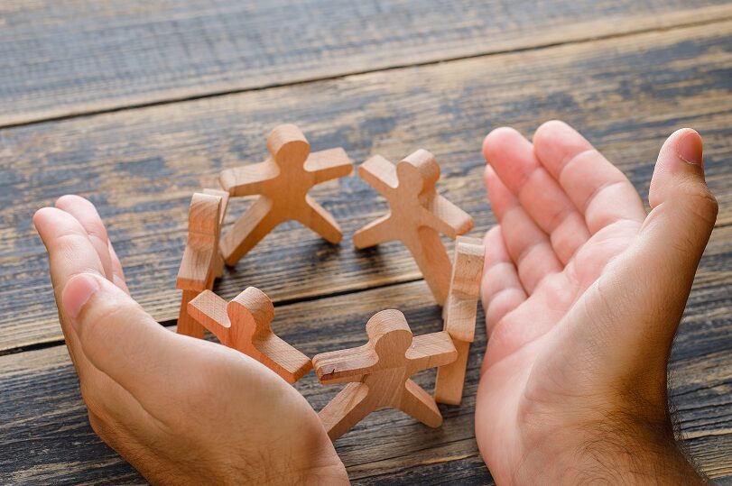 wooden figures protected by hands