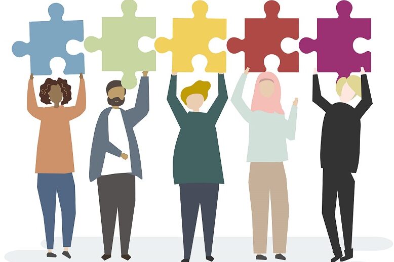 Diverse group of people holding up interconnecting jigsaw pieces.