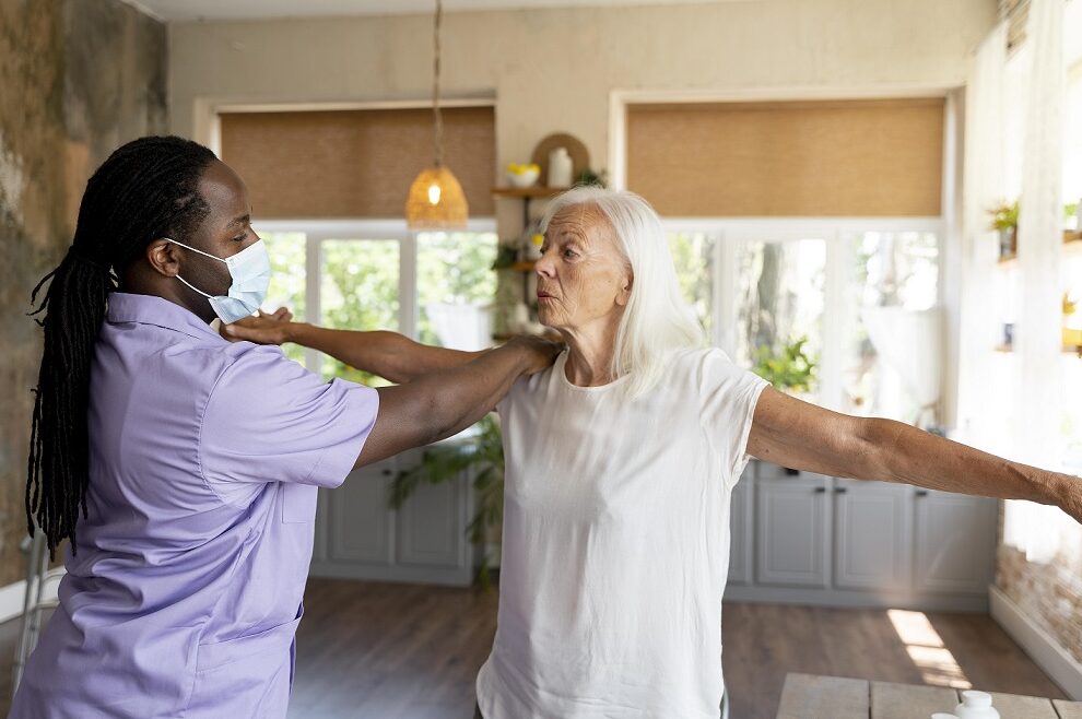 male-care-worker-taking--old-woman through her exercises.