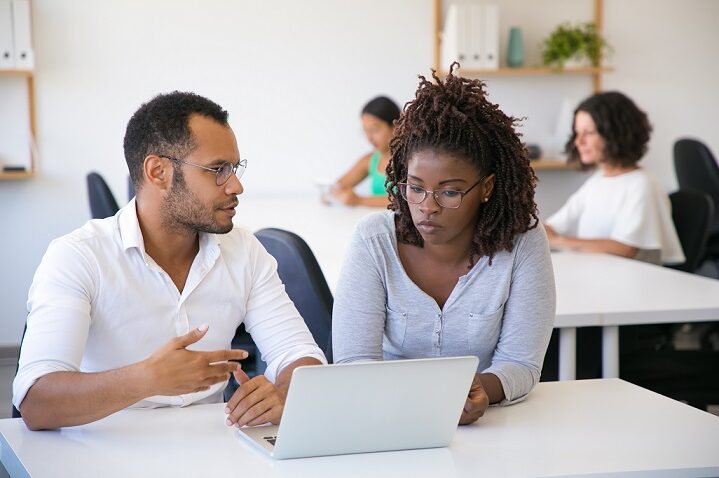 man and woman discussing data in front of a laptop