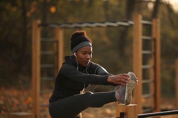 Black female athlete doing stretching exercises while warming up at the park.